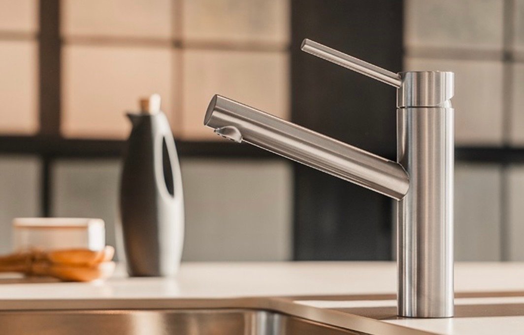 Mitigeur de cuisine en inox brossé au-dessus d'un évier : robinetterie et appareils sanitaires, plombier à Bulle